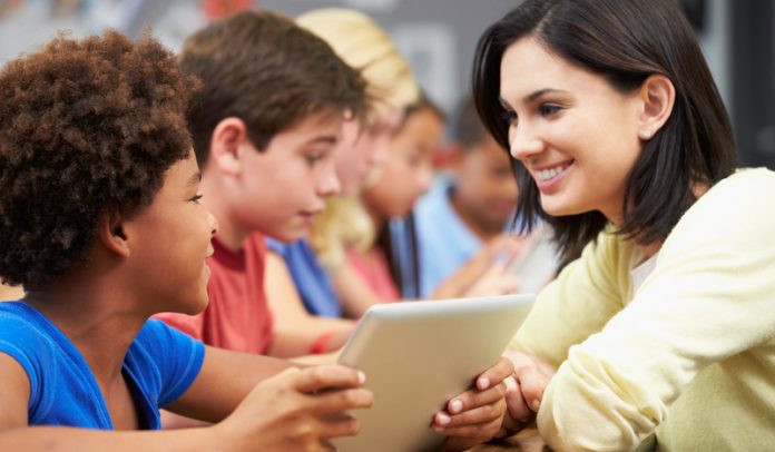 Pupils In Class Using Digital Tablet With Teacher