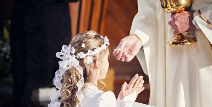 Communion and clergyman. First Holy Communion